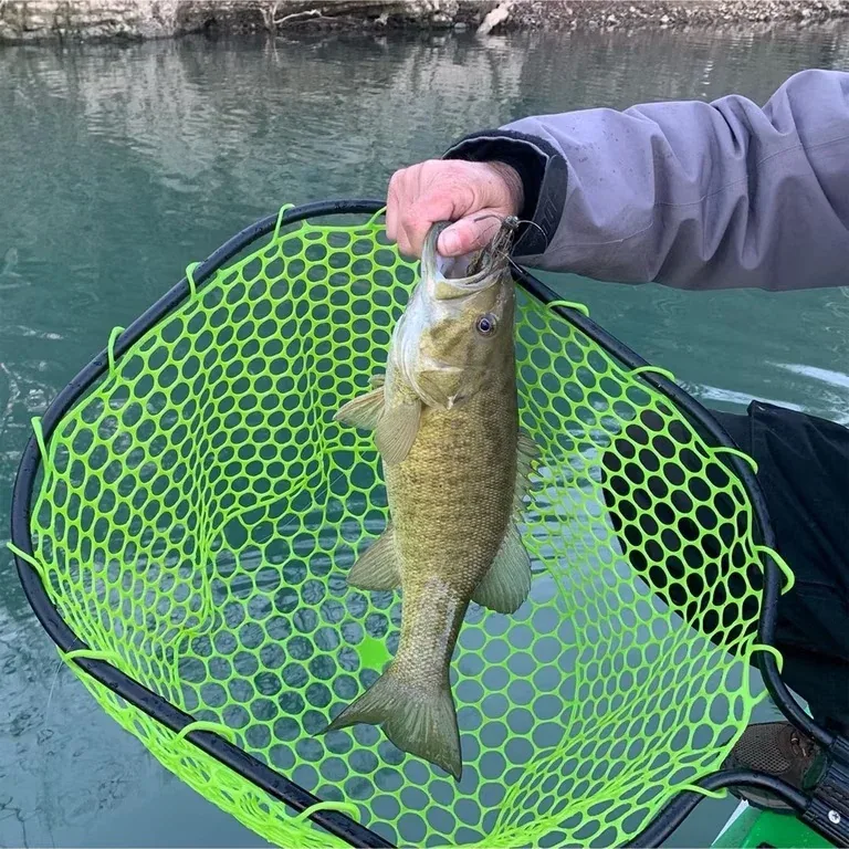 Pescador sacando un black bass del agua con una sacadera de malla sin nudos