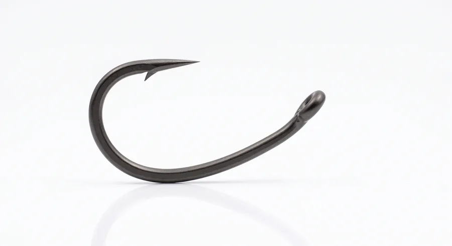 Anzuelos curvados de carpfishing sueltos sobre una superficie junto a un hair rig montado