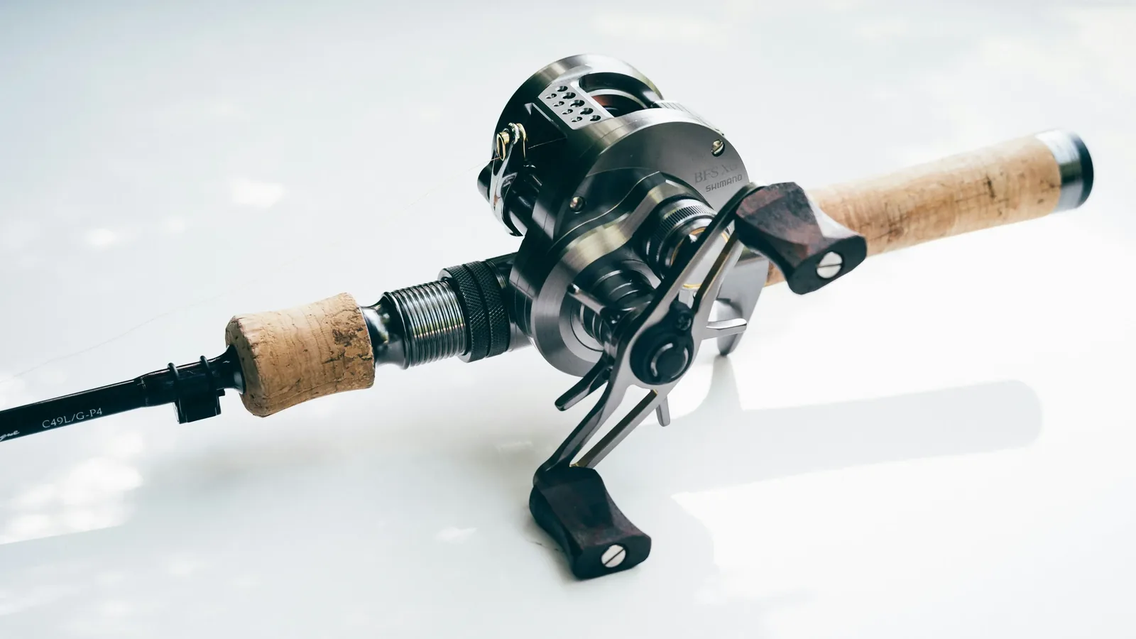 Carrete de casting baitcaster montado en una caña, sujeto por un pescador de black bass