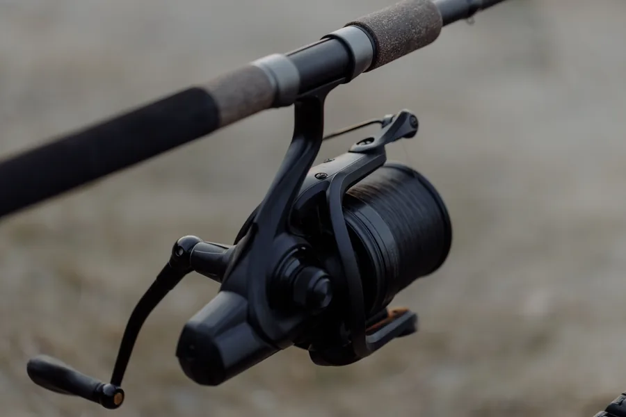 Carrete de surfcasting robusto con bobina grande de gran capacidad de hilo sobre fondo de playa