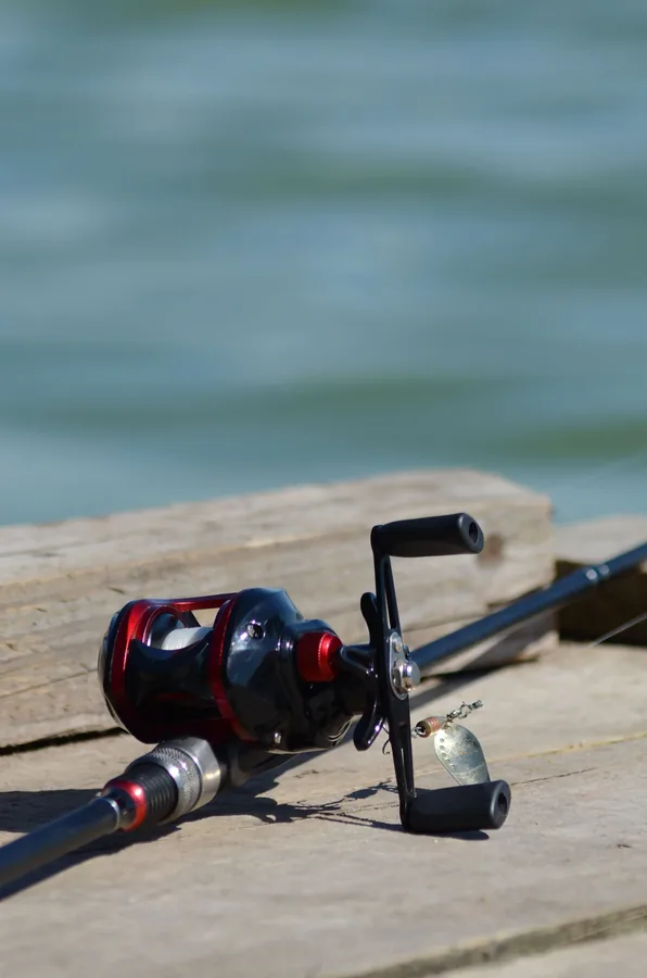 Pescador de black bass lanzando con una caña de casting y carrete baitcaster montado, en barca