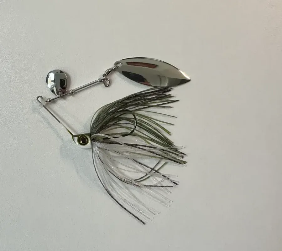 Spinnerbait con palas metálicas giratorias y falda de silicona sumergido en agua turbia
